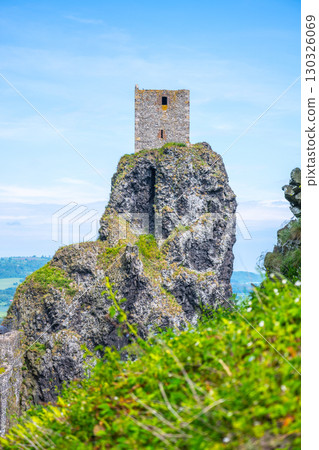 Trosky Castle Ruins are located in Bohemian Paradise, Czechia, showcasing medieval architecture against a stunning natural landscape. The tower stands dramatically atop a rocky formation. Trosky Castle Ruins are located in Bohemian Paradise, Czechia, showcasing medieval architecture against a stunning natural landscape. The tower stands dramatically atop a rocky formation. 130326069