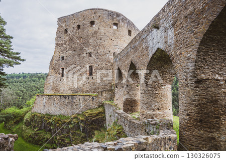 The Gothic Bridge connects ancient stone structures of Velhartice Castle surrounded by lush greenery in Czechia. Visitors admire the historical architecture and stunning landscape below. The Gothic Bridge connects ancient stone structures of Velhartice Castle surrounded by lush greenery in Czechia. Visitors admire the historical architecture and stunning landscape below. 130326075