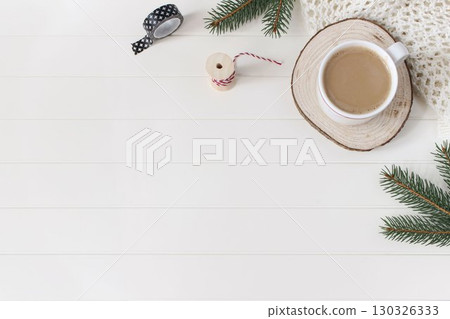 Christmas stationery still life. Cup of coffee, cut wooden round board. Green Christmas fir tree branches, wrapping tapes on white wooden table background. Winter festive flat lay, top view corner 130326333