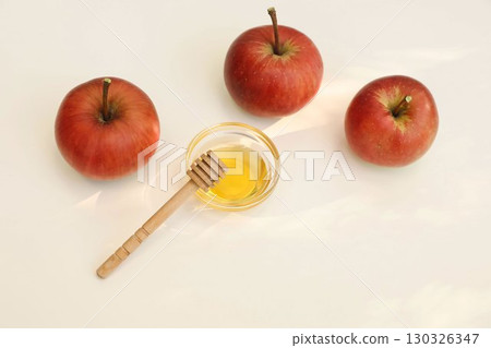Autumn seasonal still life scene. Red apples, bowl of honey, wooden dipper isolated on beige table background in sunlight. Fall, Rosh Hashanah, Thanksgiving holiday banner. Gardening. Flatlay top view 130326347