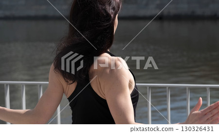 A strong woman raises her arms, showcasing toned muscles and determination. This image represents fitness, self-discipline, and body confidence. 130326431