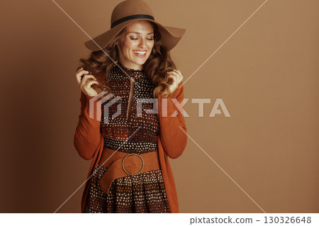 Cheerful Woman Adjusting Hair in Autumn Look 130326648