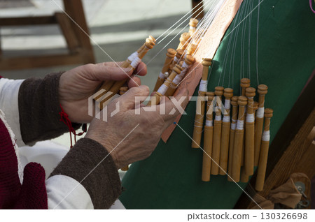 close-up of the hands of an elderly woman knitting with bobbin lace. 130326698