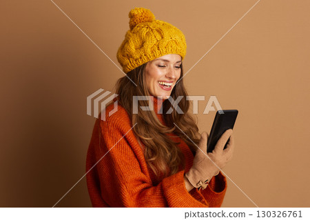 Smiling Woman Browsing Smartphone in Cozy Beret Smiling Woman Browsing Smartphone in Cozy Beret 130326761