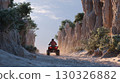 Tourist riding quad exploring desert canyon at sunset 130326882