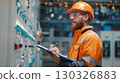Industrial engineer taking notes while inspecting electrical panel in factory 130326883