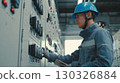 Industrial engineer taking notes while inspecting electrical panel in factory 130326884