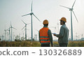 Engineers observing wind turbine operation at dusk in a wind farm 130326889