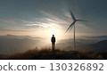 Businessman walking in field with wind turbine, investing in green energy 130326892