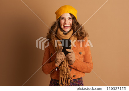 Smiling Woman with Smartphone Looks at Camera 130327155