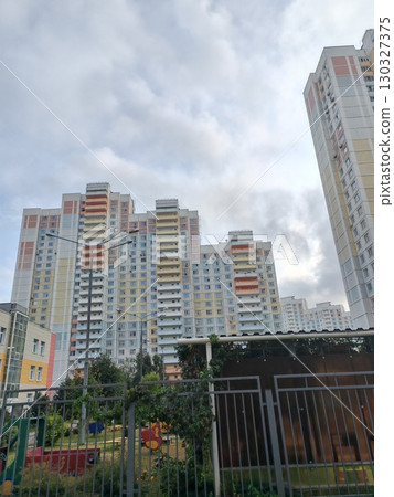A tall apartment building with pastel-colored balconies and windows, located in a residential area. The structure captures the urban residential lifestyle, emphasizing functionality and density in A tall apartment building with pastel-colored balconies and windows, located in a residential area. The structure captures the urban residential lifestyle, emphasizing functionality and density in 130327375