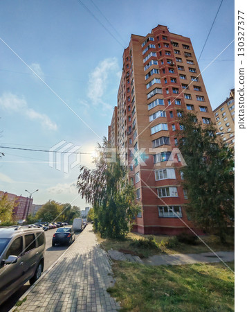 A modern apartment building with a red and beige brick facade, multiple windows, and balconies. This urban structure highlights the straightforward design and functionality of residential housing in A modern apartment building with a red and beige brick facade, multiple windows, and balconies. This urban structure highlights the straightforward design and functionality of residential housing in 130327377
