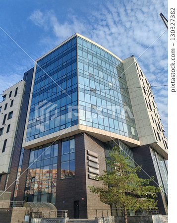 contemporary building with sharp angles, glass windows, and light paneling, reflecting modern architectural trends. The structure stands out as a symbol of urban growth and sleek design. contemporary building with sharp angles, glass windows, and light paneling, reflecting modern architectural trends. The structure stands out as a symbol of urban growth and sleek design. 130327382