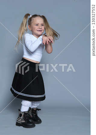 little girl strikes a playful pose, mid-motion, as if dancing in the studio. Her energetic expression and stylish outfit make this photo perfect for capturing the joy and spontaneity of childhood. little girl strikes a playful pose, mid-motion, as if dancing in the studio. Her energetic expression and stylish outfit make this photo perfect for capturing the joy and spontaneity of childhood. 130327552