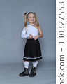 A 5-year-old girl confidently models a trendy one-shoulder top and pleated skirt. The image highlights self-assurance and early fashion awareness, capturing the concept of youthful confidence in style 130327553