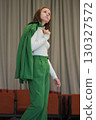 A stylish woman carrying her jacket over her shoulder, exuding elegance and confidence. The neutral background emphasizes her professional demeanor. 130327572
