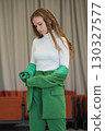 A modern portrait of a woman adjusting her jacket, with a determined look and neutral interior background, embodying confidence and elegance. 130327577