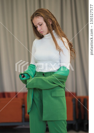 A modern portrait of a woman adjusting her jacket, with a determined look and neutral interior background, embodying confidence and elegance. 130327577