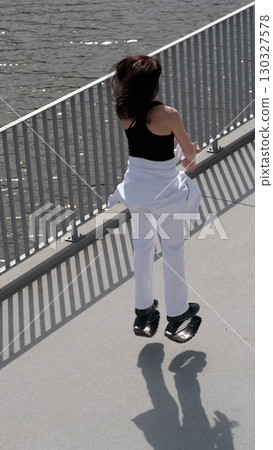 A woman in Kangoo Jumps boots jumps gracefully along a waterfront promenade, her hair moving with the motion. The rise of alternative fitness methods highlights the modern trend of making exercise 130327578