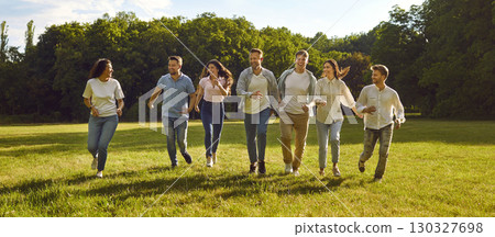 Cheerful young men and women having fun running on green lawn in park on sunny summer day. Cheerful young men and women having fun running on green lawn in park on sunny summer day. 130327698