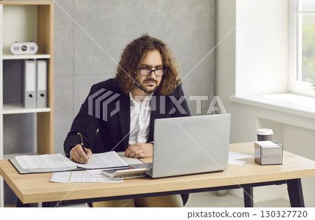 Bearded business man working at the desk on workplace at office looking at laptop monitor screen. Bearded business man working at the desk on workplace at office looking at laptop monitor screen. 130327720