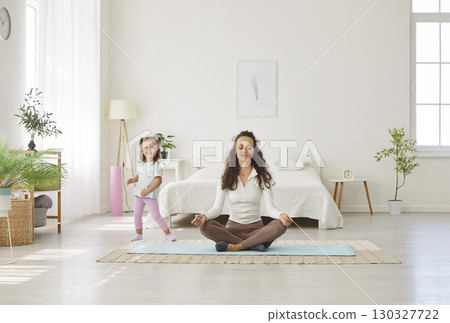 Happy calm mother resting in lotus pose, breathing techniques, mindfulness practice with daughter Happy calm mother resting in lotus pose, breathing techniques, mindfulness practice with daughter 130327722