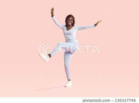 Portrait of happy young African American girl in casual clothes dancing on pink background 130327748