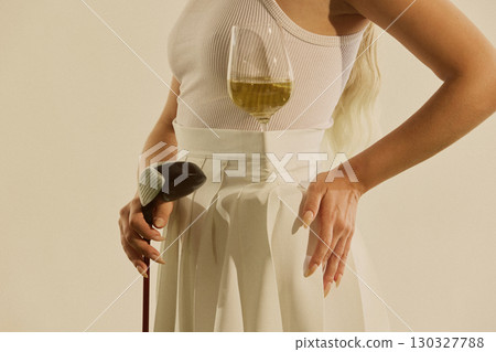 Woman golfer holding club with wine glass balanced on chest elegant stylish mood 130327788