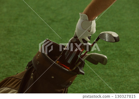 Hand in golf glove placing liquor bottle into golf bag with clubs stylish atmosphere Hand in golf glove placing liquor bottle into golf bag with clubs stylish atmosphere 130327815