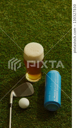 Pint of beer with golf club ball and blue can on grass refreshing casual mood 130327830