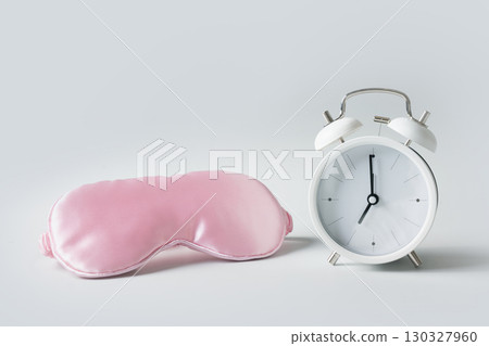 Pink sleeping mask and white alarm clock. Concept of sleep, health care. 130327960