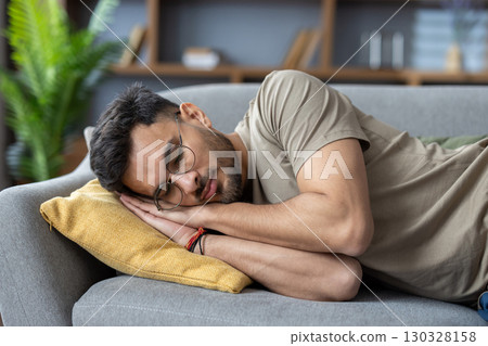 Close-up photo of a young Indian man sleeping and relaxing on the couch at home. 130328158