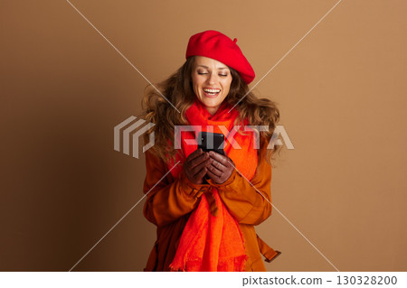Joyful Woman Laughing at Smartphone in Fall Attire Joyful Woman Laughing at Smartphone in Fall Attire 130328200