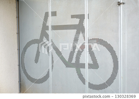 Indoor bicycle parking area featuring a modern design with a perforated metal screen displaying a bicycle silhouette 130328369
