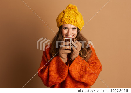 Young Woman Enjoying a Hot Mug in Cozy Winter Attire 130328416