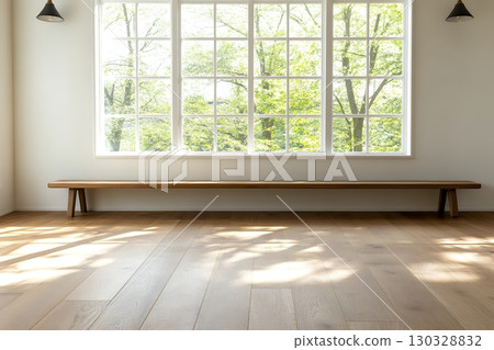 A long wooden bench sits beneath a large window overlooking a lush green landscape in a bright, minimalist room 130328832