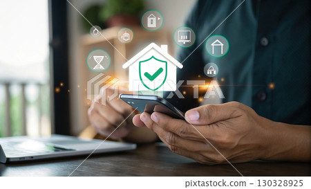Smartphone held by person with digital home security icons and shield symbol, representing smart home protection and technology safety Smartphone held by person with digital home security icons and shield symbol, representing smart home protection and technology safety 130328925
