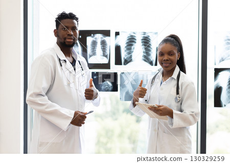 Collaborative team of male and female medical professionals analyzing diagnostic x-rays in clinical environment. 130329259