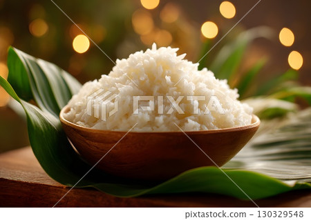 A bowl of white rice served on a banana leaf, symbolizing the traditional Onam Sadya feast in Kerala, India. The background features soft bokeh lights. 130329548