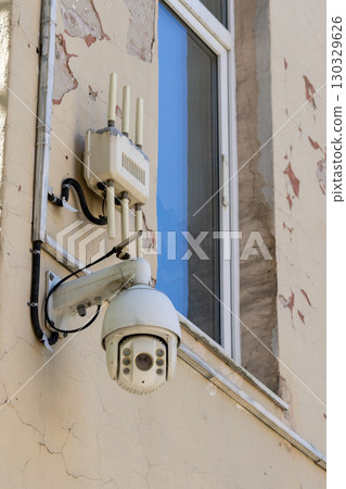 Camera is mounted on a wall. The camera is white and has a black lens 130329626