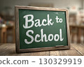 A chalkboard with the phrase 'Back to School' written in white chalk. The background features a blurred classroom setting with wooden desks. 130329919