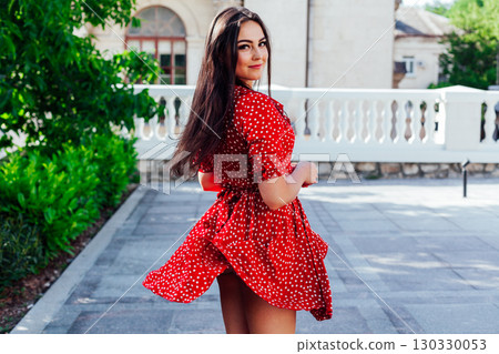 Stylish girl in summer outfit: , red dress, white bag walk on old city streets Stylish girl in summer outfit: , red dress, white bag walk on old city streets 130330053
