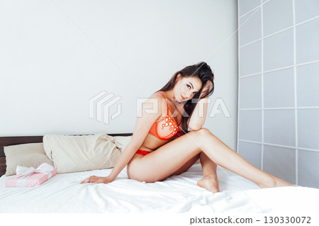 Portrait of brunette woman in red lingerie enjoying lying in bed 130330072