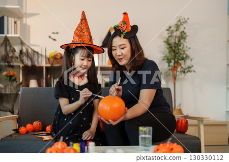 Mother and daughter painting pumpkins for Halloween celebration Mother and daughter painting pumpkins for Halloween celebration 130330112