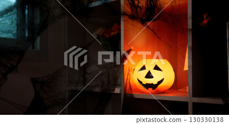 Halloween ambiance. A glowing pumpkin surrounded by spooky decorations in a cozy setting. Halloween ambiance. A glowing pumpkin surrounded by spooky decorations in a cozy setting. 130330138
