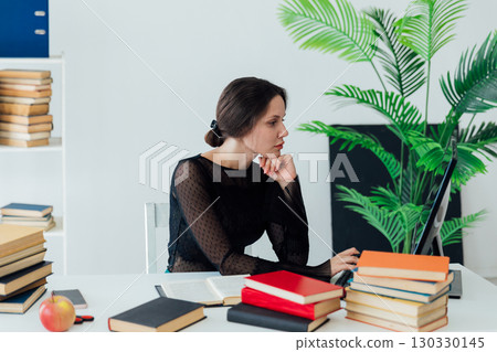 A professional employee is seen deeply engaged with his tasks, writing notes beside her laptop. 130330145
