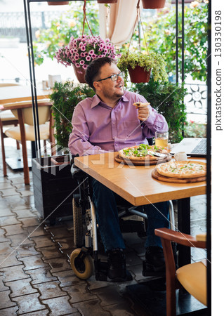 Man in wheelchair dining in street restaurant Man in wheelchair dining in street restaurant 130330198