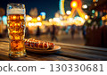 A glass of beer and a plate of sausages on a wooden table at night. Colorful lights from a carnival in the background. Oktoberfest celebration in Bavaria, Germany. 130330681
