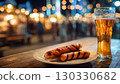 A plate of grilled sausages next to a glass of beer. The background features a festive atmosphere with blurred lights, typical of Oktoberfest in Bavaria, Germany. 130330682