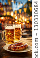 Two large mugs of golden beer sit on a wooden table next to a plate of grilled sausages. Colorful flags decorate the background, creating a festive atmosphere. 130330684